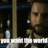 a man with a beard is standing in front of a bar and says you want the world