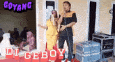 a man and a woman singing into microphones with the words goyang di geboy behind them