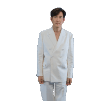 a man in a white suit is standing with his hands in his pockets