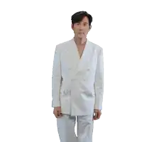 a man in a white suit is standing with his hands in his pockets