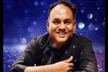 a man in a black shirt is giving a thumbs up sign