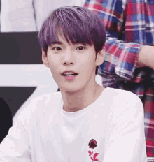a young man with purple hair is wearing a white t-shirt with a rose embroidered on it .
