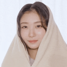 a woman with her head wrapped in a blanket looks at the camera