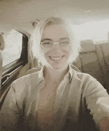 a woman wearing glasses is taking a selfie in the back seat of a car