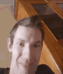 a close up of a man 's face in front of a cabinet
