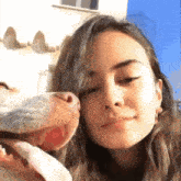 a woman is holding a dog 's nose while looking at the camera .