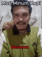 a man wearing headphones and a green shirt that says mari minum kopi