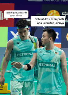 two badminton players wearing petronas jerseys are talking