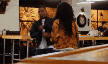 a man and a woman are standing in a restaurant with a dart board on the wall .