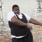 a man is standing in front of a brick wall dancing .