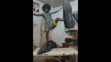 a little girl is jumping in the air in a room while wearing a dress .