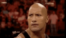 the rock is making a funny face in front of a crowd .