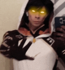 a woman is taking a selfie with her phone while wearing a hoodie and sunglasses .