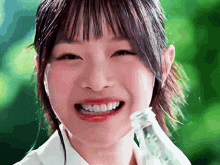 a girl is holding a bottle in her mouth and smiling