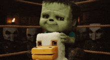 a green monster is holding a stuffed animal in a ring