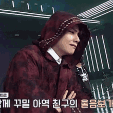 a man wearing a hooded jacket with korean writing on the bottom right