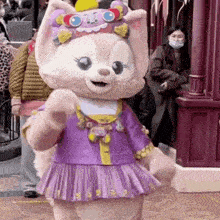 a stuffed animal wearing a purple dress and a hat is standing in front of a building .
