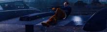 a man is laying on the ground holding a gun and shooting it .