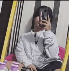 a person is taking a selfie in front of a mirror with a cell phone .