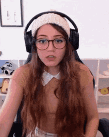 a woman wearing glasses and headphones is sitting in a chair and making a funny face .