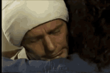 a man wearing a white hat and a bandage on his head is hugging another man .