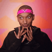 a man with a pink bandana on his head making a face