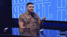a man is sitting at a table with a microphone in front of a screen that says chris van fleet