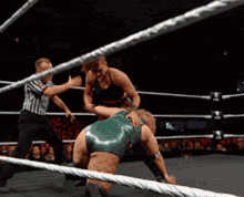 two women wrestling in a ring with a referee watching