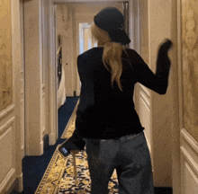 a woman walking down a hallway holding a cell phone