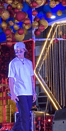 a man in a white shirt is standing in front of a stage with christmas decorations hanging from the ceiling