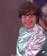 a man wearing glasses and a silver shirt is making a face