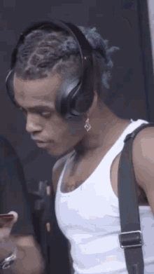 a young man wearing headphones and a white tank top .