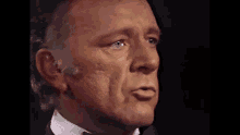 a close up of a man 's face in a tuxedo and white shirt