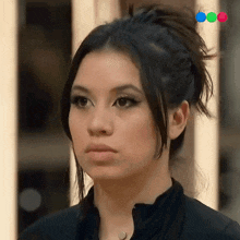 a close up of a woman 's face with a bun on her head