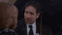 a man in a suit and tie is holding a black umbrella