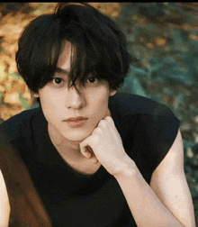 a young man with his hand on his chin looking at the camera