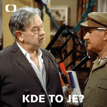 two men standing next to each other with the words kde to je on the bottom right