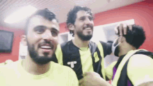 a group of men are hugging each other in a locker room
