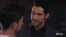two men looking at each other with a netflix logo in the background