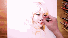 a person is drawing a woman 's face with colored pencils on a table