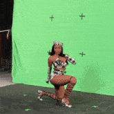 a woman in a zebra print outfit is kneeling on a green screen