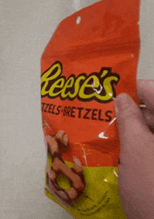 a person is holding a bag of reese 's pretzels in their hand