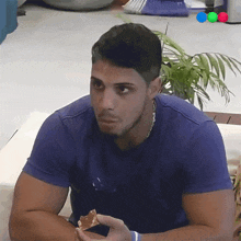 a man wearing a blue shirt is eating a piece of food