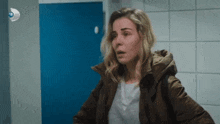 a woman in a brown jacket is standing in a bathroom .