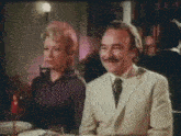 a man and woman are sitting at a table in a restaurant and smiling .