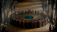 a group of people sit around a round table with a blue circle in the center