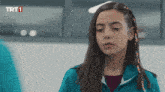 a girl with braids in her hair looks at the camera with the trt1 logo in the corner