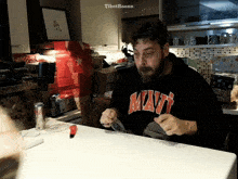 a man wearing a mavi sweatshirt sits at a kitchen counter