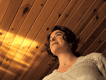 a woman wearing a white sweater is looking up at the ceiling
