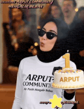 a woman blowing a kiss while holding a cake that says arput community